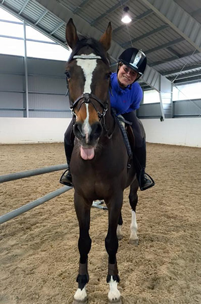 woman riding a dark brown horse in an arena