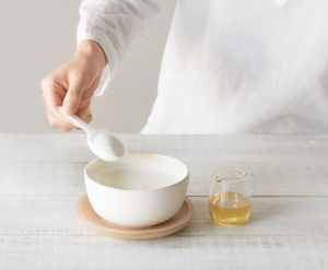 person scooping collagen powder from white bowl